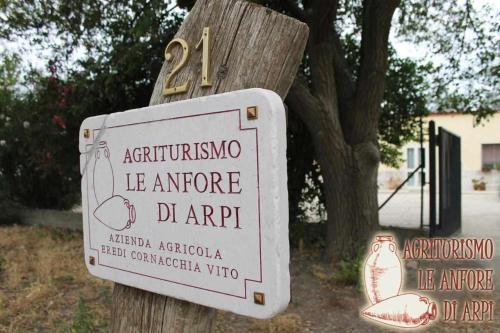 a sign on a wooden pole in front of a tree at Le Anfore di Arpi in Foggia