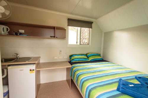 um pequeno quarto com uma cama e um lavatório em Meekatharra Accommodation Centre em Meekatharra