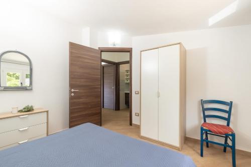 a bedroom with a bed and a chair and a mirror at Mansarda Moro in Baunei