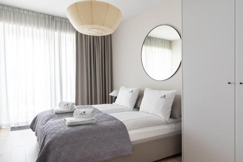 een witte slaapkamer met een bed en een spiegel bij Lion Apartments - Gdynia Yacht Park with Sea View in Gdynia
