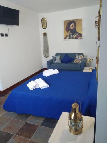 a bedroom with a blue bed and a couch at Elios bed and breakfast in Villa - Fuscaldo in Pietrapiana