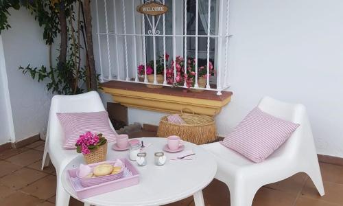 einen weißen Tisch mit 2 Stühlen und ein Fenster mit Blumen in der Unterkunft Mi casita del Bosque in El Bosque