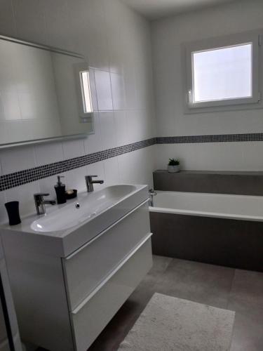 une salle de bain avec un lavabo, une baignoire et un miroir dans l'établissement Maison familiale avec jardin de 1500m2, à Saint-Genès-de-Fronsac