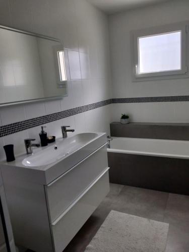 a bathroom with a sink and a tub and a mirror at Maison familiale avec jardin de 1500m2 in Saint-Genès-de-Fronsac