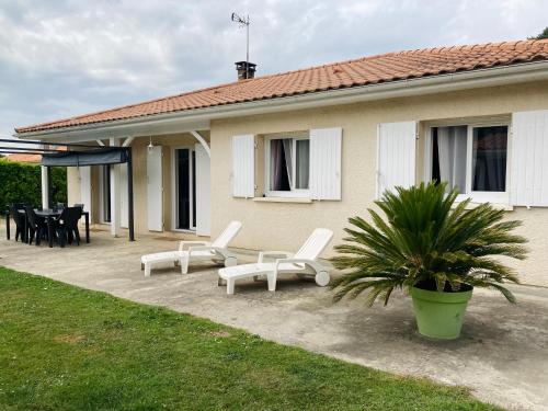 um pátio com cadeiras brancas, uma mesa e uma casa em Maison familiale avec jardin de 1500m2 em Saint-Genès-de-Fronsac