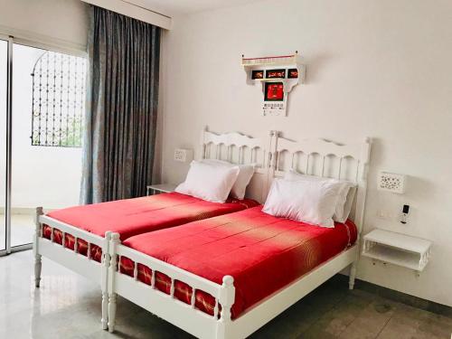 a bedroom with a white bed with red sheets at Résidence Neffati in Hammamet