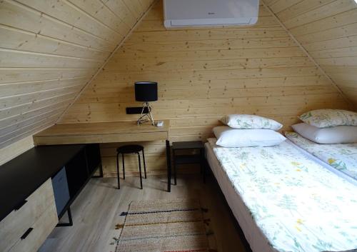 a room with two beds and a desk in a cabin at Ptasia Zatoka in Augustów