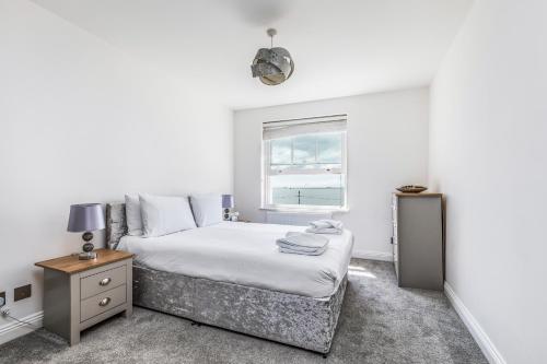 Habitación blanca con cama y ventana en Ashbys Seafront 2 Bedroom Apartment en Portsmouth