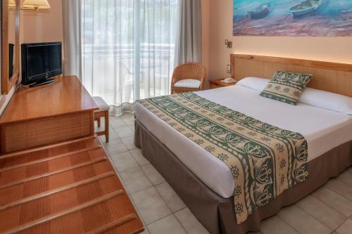 トッサ・デ・マールにあるGHT Oasis Tossa & Spaのベッドとテレビが備わるホテルルームです。