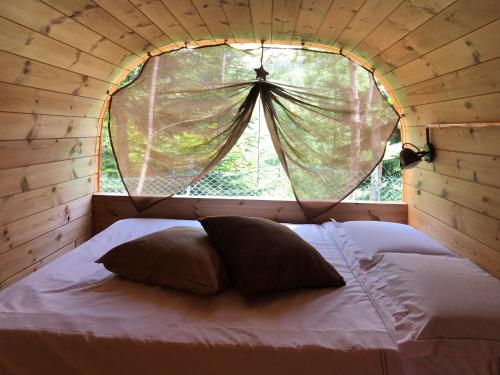 Cama en habitación pequeña con ventana en Campeggio il Bosco, en Entracque