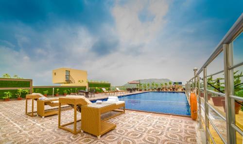 a balcony with a pool and tables and chairs at Clarion Inn Jaipur in Jaipur