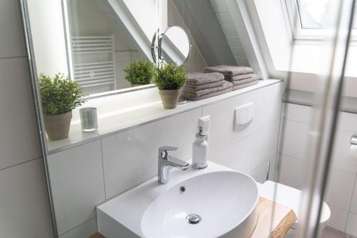 a white bathroom with a sink and a mirror at Domizil am Ostseewald - Kornrade in Zingst
