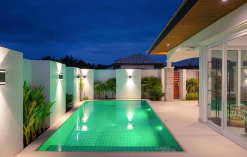 a swimming pool in the backyard of a house at night at My Orchid HuaHin in Hua Hin