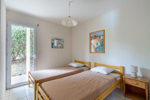 deux lits dans une chambre avec une fenêtre dans l'établissement Villa piscine pour 8 à Lacanau, à Lacanau