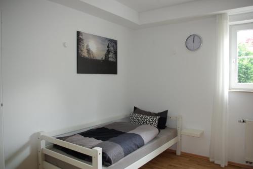 een bed in een witte kamer met een klok aan de muur bij Ferienwohnung am Hermann in Detmold