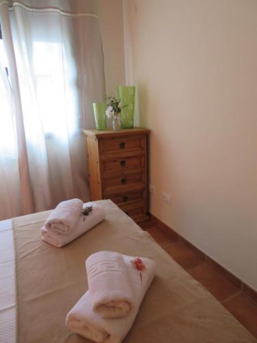 a bedroom with two towels on a bed with a dresser at ALOJAMIENTO YOLANDA CAZORLA in Cazorla