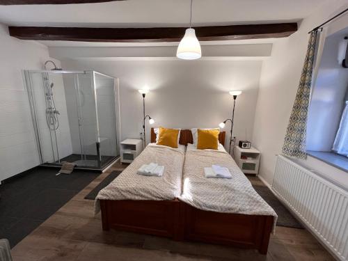 a bedroom with a bed with yellow pillows and a shower at Vitamin K73 Vendégház in Boldogkőváralja