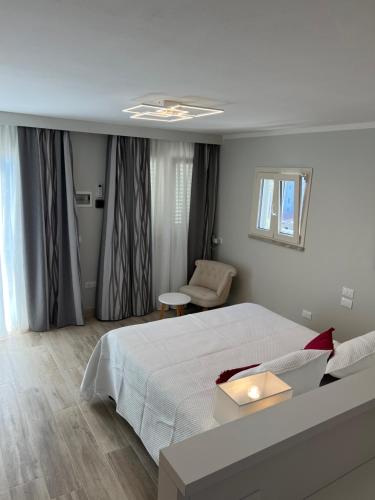 a white bedroom with a bed and a chair at Hotel La Bitta in Marina di Pietrasanta