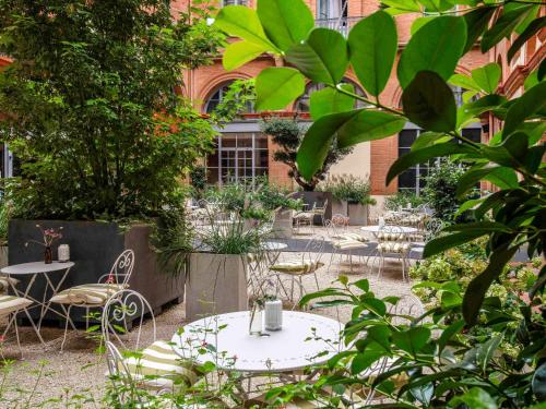 Ibis Styles Toulouse Capitole في تولوز: ساحة مع طاولات وكراسي ومبنى