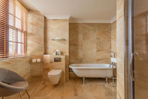 a bathroom with a tub and a toilet and a sink at Gleddoch Golf & Spa Resort in Langbank