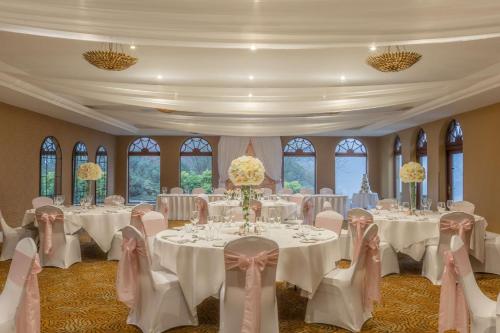 a banquet hall with white tables and chairs and windows at Gleddoch Golf & Spa Resort in Langbank