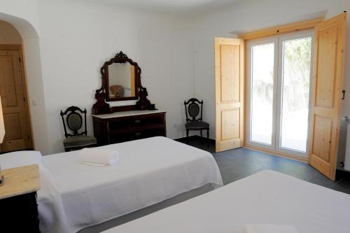 a bedroom with two beds and a mirror and a window at Casa das Rendufas- Turismo Rural com Figos in Rendufas da Estrada