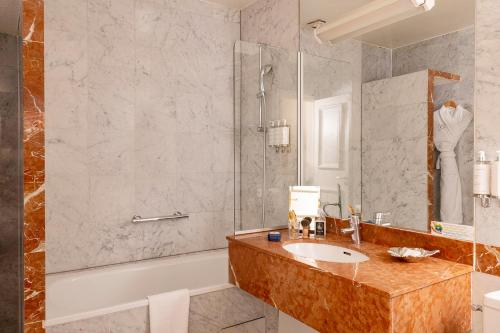 y baño con lavabo, bañera y ducha. en Hotel De Seine, en París