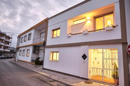 a white building with windows on the side of a street at Casas do Portinho in Marinha Grande