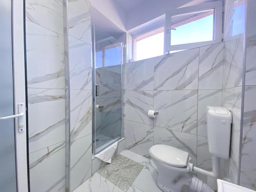 a white bathroom with a toilet and a window at Hotel Class in Oradea