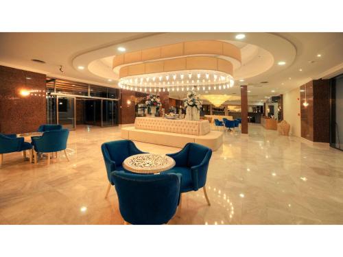 a lobby with blue chairs and a counter in a building at Jasmine Court Hotel & Casino in Kérynia