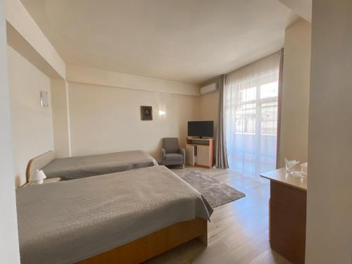 a bedroom with two beds and a desk and a television at Hotel Class in Oradea