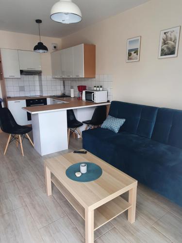 a living room with a blue couch and a table at Morze i Las in Dziwnówek