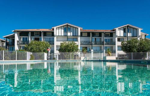um grande edifício com uma piscina em frente em Studio cabine résidence 4 étoiles piscine tennis golf parking privé em Bidart