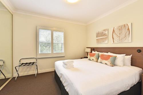 una camera da letto con un grande letto con lenzuola bianche di Villa 2br Pinot Nois Villa located within Cypress Lakes Resort a Pokolbin