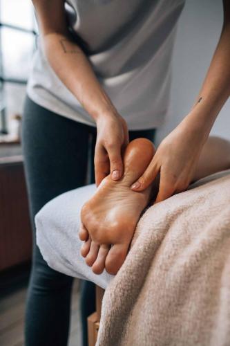 a woman with her hands on a foot on a bed at Cihelny Golf & Wellness Resort in Karlovy Vary