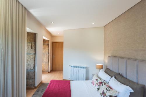 um quarto com uma grande cama branca e uma parede em Casa Dona Maria - Armamar Douro em Armamar