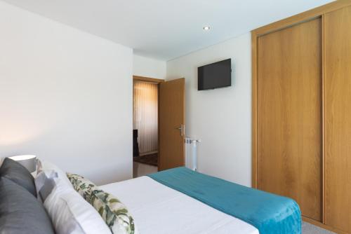 a bedroom with a bed and a tv on the wall at Casa Dona Maria - Armamar Douro in Armamar