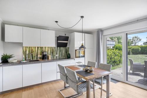 a kitchen with white cabinets and a table and chairs at Zur Meeresmuschel Nr.10 in Zingst