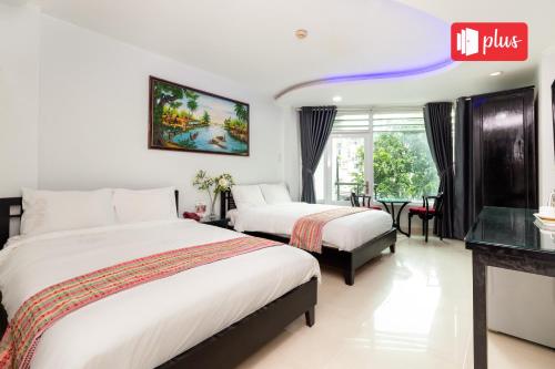 a hotel room with two beds and a table at Saigon Pink Hotel in Ho Chi Minh City