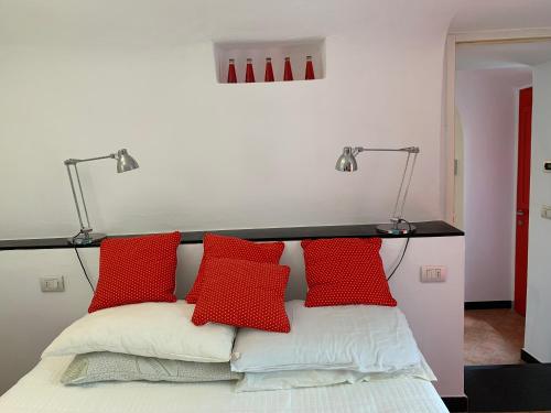 un letto con tre cuscini rossi e due lampade sopra di Medieval mountain setting with private garden a Colletta