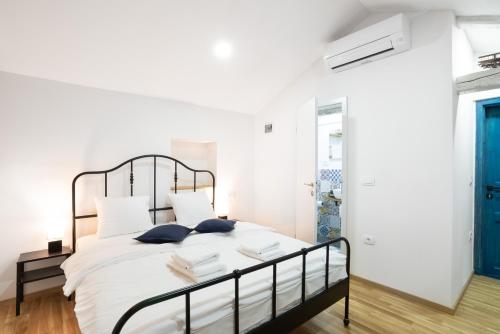 1 dormitorio con cama con sábanas blancas y puerta azul en Istrian Casa Ladonia by Locap Group, en Portorož