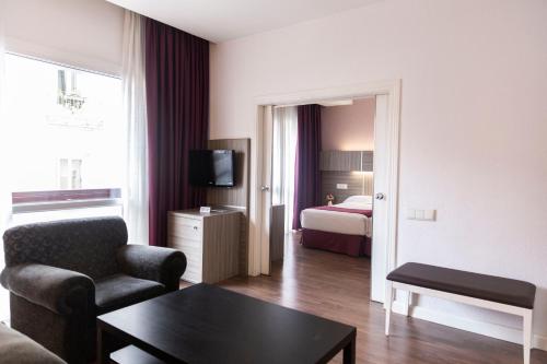 ein Wohnzimmer mit einem Sofa und ein Zimmer mit einem Bett in der Unterkunft Hotel Serrano in Madrid