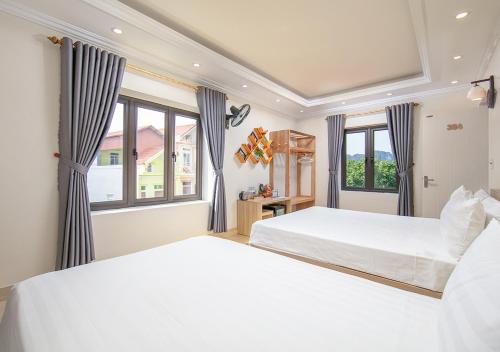 two beds in a room with two windows at Della Luna Tam Cốc in Ninh Binh