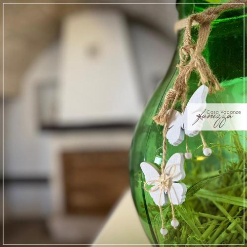 a green vase with white flowers in it at Trullo Eliana in Alberobello