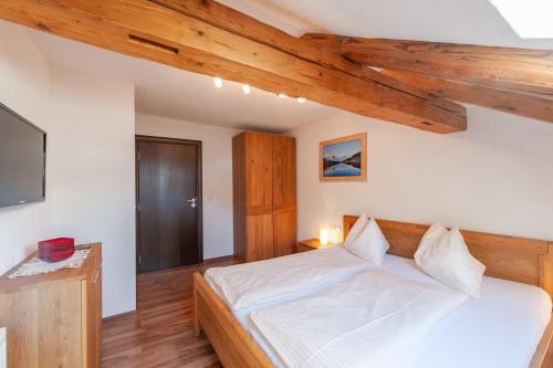 - une chambre avec un lit blanc et des plafonds en bois dans l'établissement Appartement 204, à Bichlbach