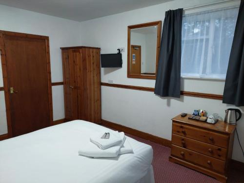 a bedroom with a bed and a dresser and a mirror at Twa Dogs Inn in Keswick