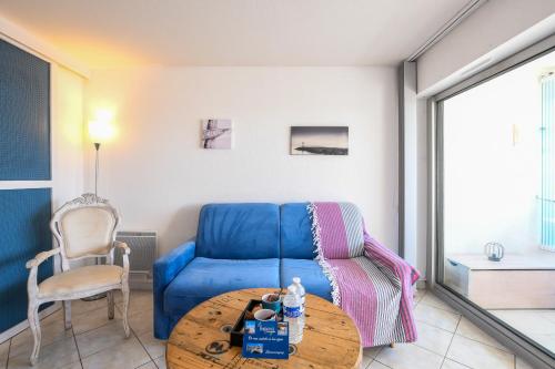 a living room with a blue couch and a table at Studio Daisy / charmant / Terrasse / lumineux / plage à 5 min in La Grande-Motte