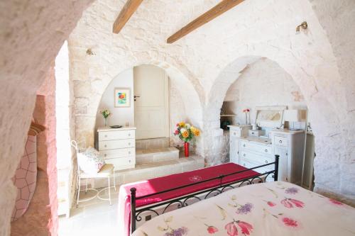 ein Schlafzimmer mit einem roten Bett in einem Steinzimmer in der Unterkunft Villa Trulli Isabella by Villa Plus in Martina Franca