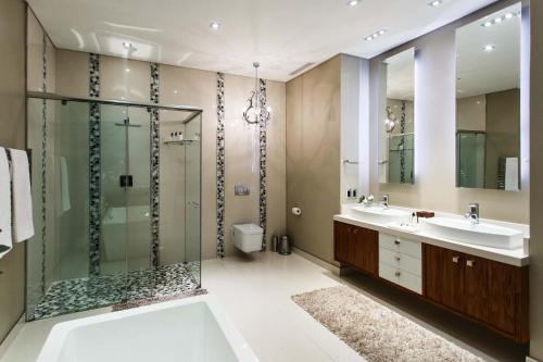 a bathroom with a shower and two sinks and a toilet at Sonas Boutique Hotel in Oudtshoorn