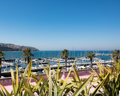 a marina with boats in the water and palm trees at Hotel Grand Koper in Koper